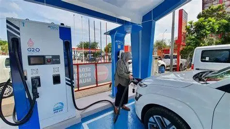 Pengisian Daya Mobil Listrik Mobil listrik sedang mengisi daya di stasiun pengisian cepat