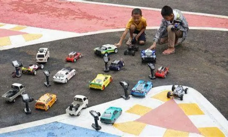 Interaksi Sosial Anak Dua orang anak sedang bermain balapan mobil remot