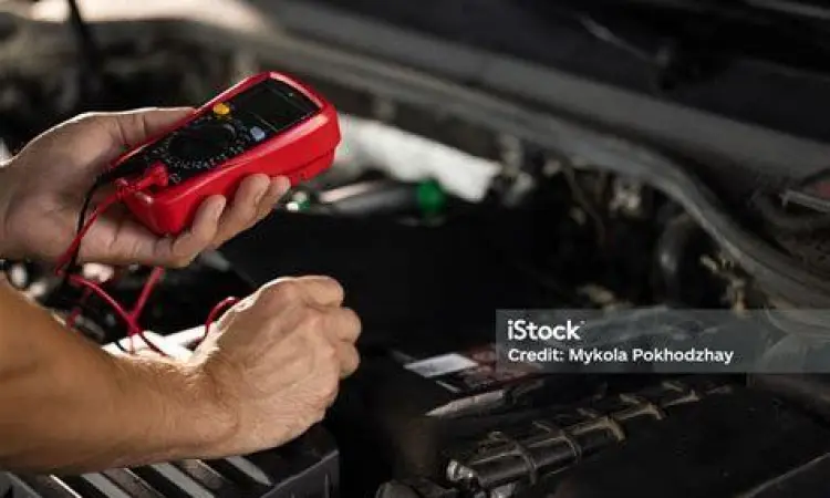 Pengecekan Voltase Aki Mekanik sedang memeriksa voltase aki mobil dengan multitester