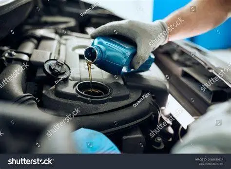 Proses Penggantian Oli Mesin Mekanik sedang menuangkan oli mesin mobil baru