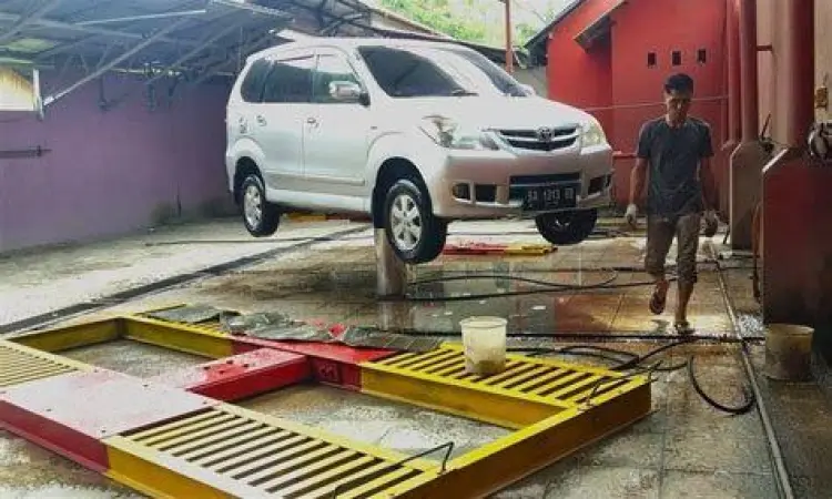 Proses pengangkatan mobil menggunakan hidrolik untuk cuci steam