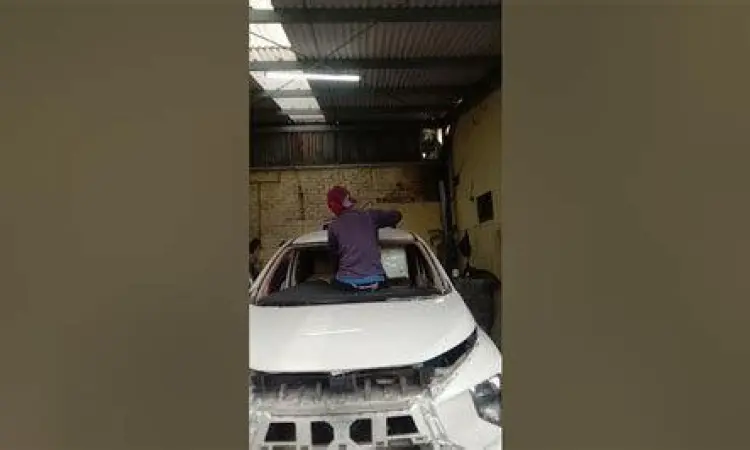 Teknisi profesional sedang memasang kaca depan mobil dengan lem khusus